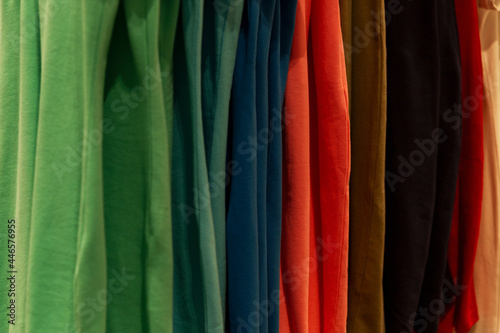 Multicolored cotton T-shirts on a hanger in a store. Close-up.