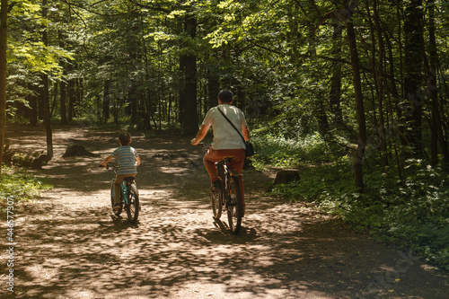 Father and son riding bicycles on a forest road. Outdoor activities and healthy lifestyle.