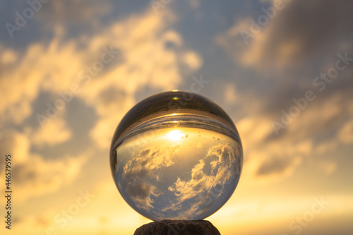 Fototapeta Naklejka Na Ścianę i Meble -  .view on the beach in beautiful sunset inside crystal ball placed on a timber by the sea. .Unconventional and beautiful natural views on the beach and sunset in a magic crystal ball. .
