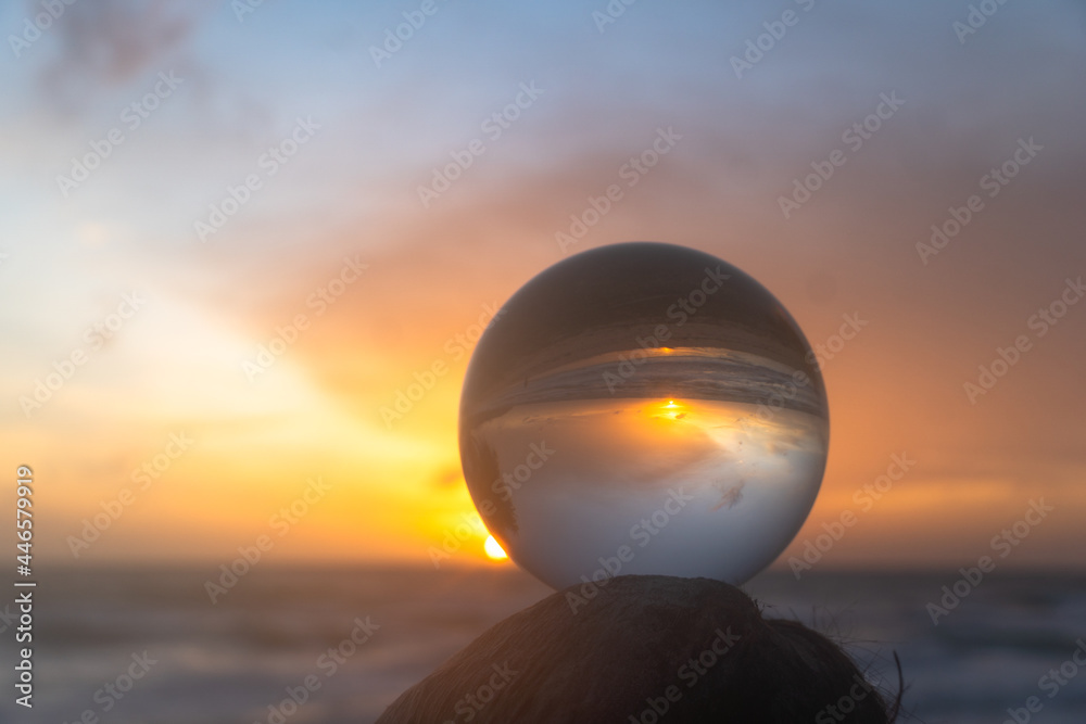 .view on the beach in beautiful sunset inside crystal ball placed on a timber by the sea. .Unconventional and beautiful natural views on the beach and sunset in a magic crystal ball. . .view on the beach in beautiful sunset inside crystal ball placed on a timber by the sea. .Unconventional and beautiful natural views on the beach and sunset in a magic crystal ball. .