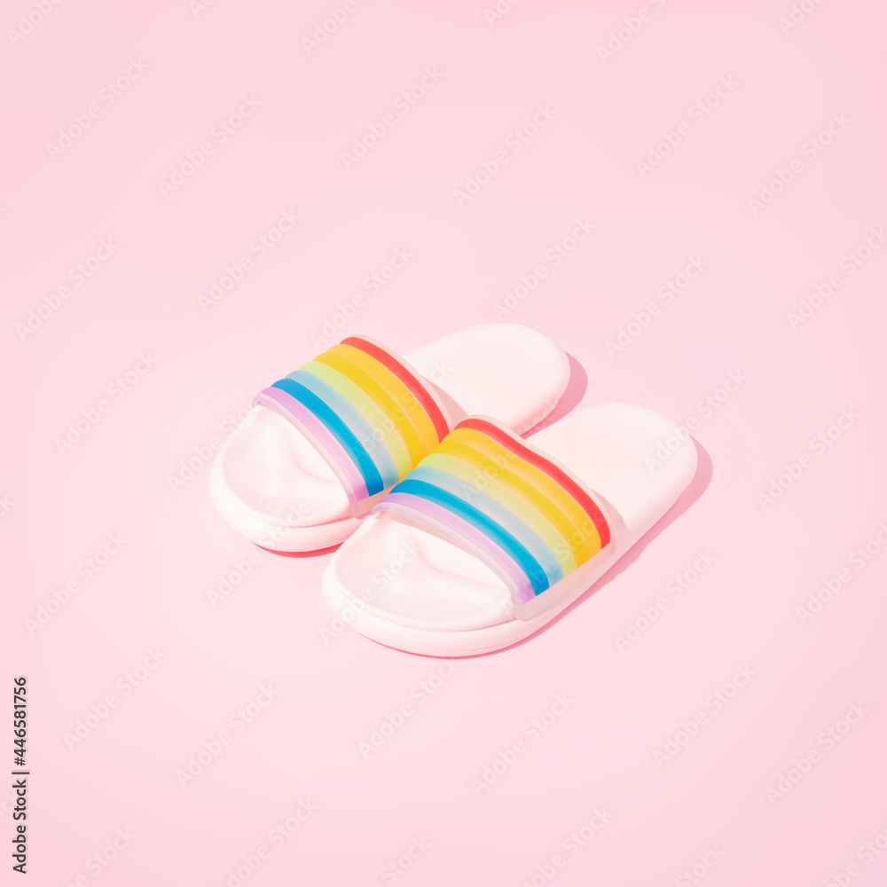 Summer slippers rainbow colors on pastel pink backgrounds. Creative minimal LGBT concept. Trendy colorful style
