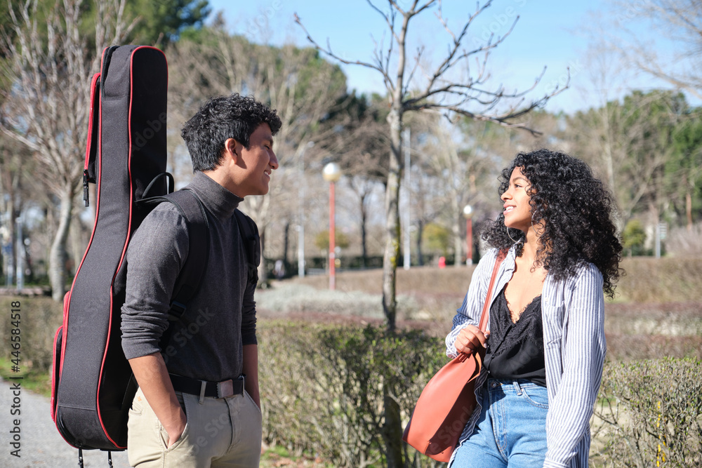 Latin friends talking at the college campus with a guitar case. University life. Latin friends talking at the college campus with a guitar case. University life.