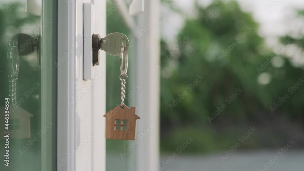 landlord for new home concept. New home for life The house key for unlocking a new house is plugged into the door. The keychain was moving as the wind on evening. landlord for new home concept. New home for life The house key for unlocking a new house is plugged into the door. The keychain was moving as the wind on evening.