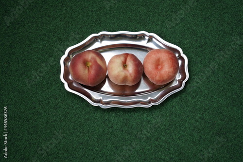 The flat peach (Prunus persica var. platycarpa), also known as the doughnut peach or Saturn peach, is a variety of peach with pale yellow fruit that is oblate in shape. Ón a silver platter.