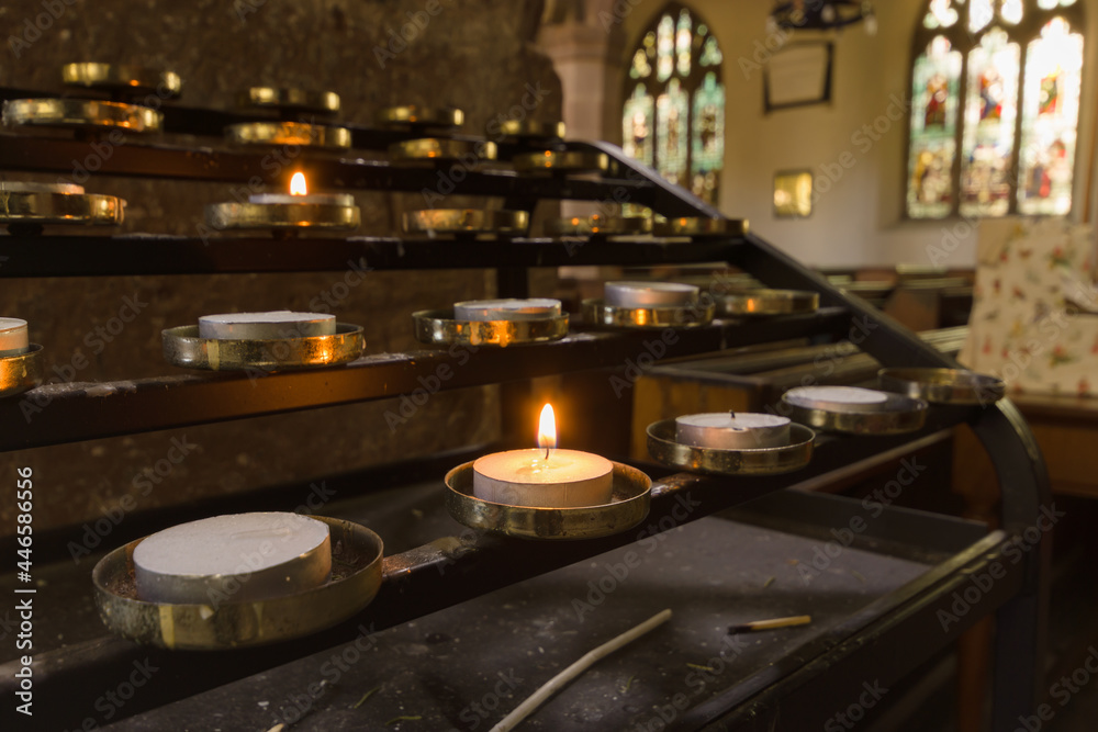 Votive candles lit as prayers for loved ones inside a Christian church