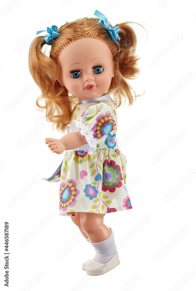 Realistic silicone doll of a teenage girl standing sideways to the viewer in a light dress, with long blonde hair gathered in ponytails, isolated on a white background. Realistic silicone doll of a teenage girl standing sideways to the viewer in a light dress, with long blonde hair gathered in ponytails, isolated on a white background.