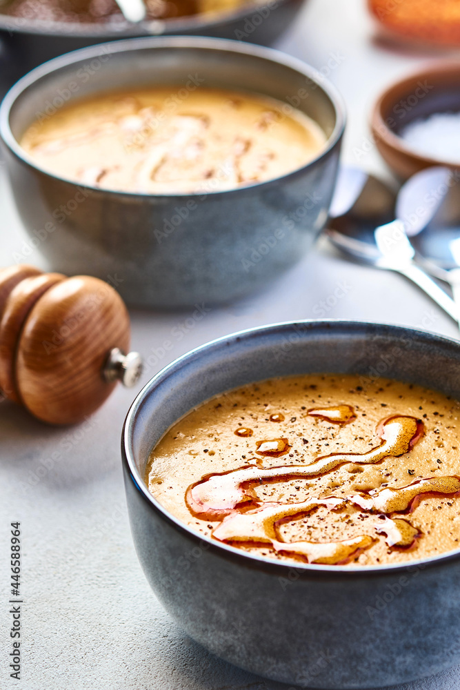 Lentil turkish yellow-coloured cream soup in a grey bowl. The second bowl is on the background. 45 angle view Lentil turkish yellow-coloured cream soup in a grey bowl. The second bowl is on the background. 45 angle view