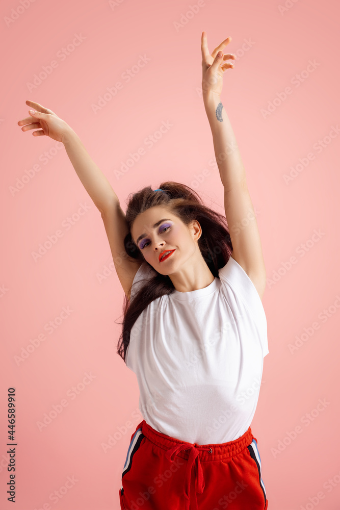 Portrait of adorable pretty young girl in retro 90s fashion style, outfits posing isolated over pink studio background. Concept of eras comparison, beauty, fashion and youth. Portrait of adorable pretty young girl in retro 90s fashion style, outfits posing isolated over pink studio background. Concept of eras comparison, beauty, fashion and youth.