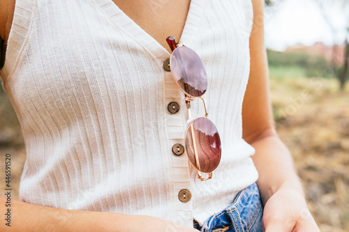 Anonymous woman with sunglasses hanging from her shirt