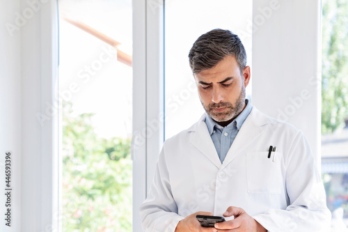 Male doctor checking smartphone in clinic