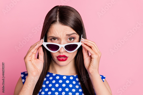Portrait of attractive suspicious glamorous girl touching specs isolated over pink pastel color background