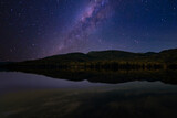 Starry night sky. The milky way is reflected in the lake. The mountains are sleeping peacefully. 