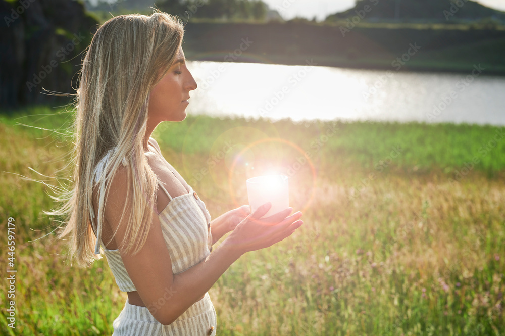 Blonde girl practicing meditation with a candle at dawn Blonde girl practicing meditation with a candle at dawn