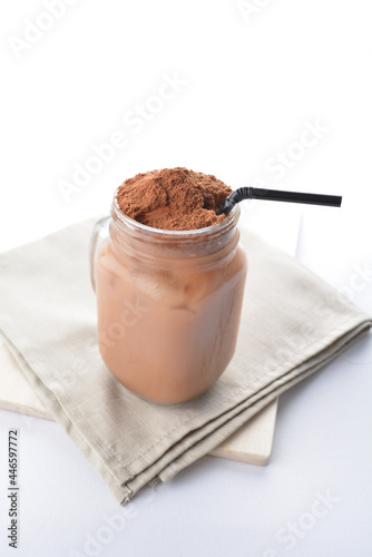 cold iced chocolate milo dinosaur with coco powder in glass jar white background asian beverage halal menu photo