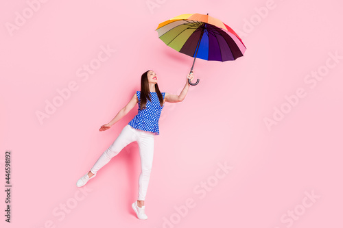 Full length body size view of attractive cheerful carefree girl holding parasol having fun dancing isolated over pink pastel color background