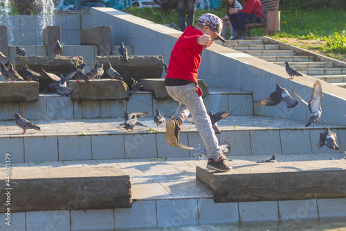 A boy jumps on the tiles on the water fountain in the summer in the park