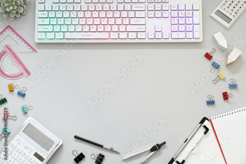 Frame of modern RGB keyboard and office stationery on light grey background, flat lay. Space for text