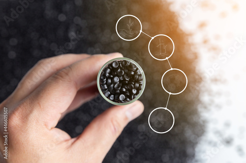 Hand holding glass bulb plastic beads. recycle icon. Save environment concept. black polymer pallet.