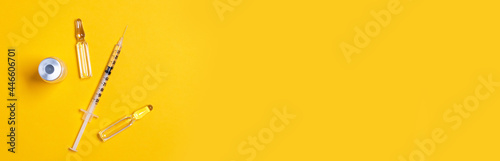 Syringe and vaccine or medicine vial on a yellow background with copy space for immunization against COVID-19. Flat lay. Beauty injections photo