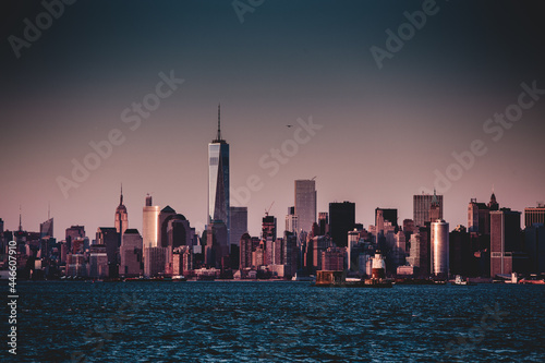 New York City Manhattan downtown skyline at dusk with skyscrapers illuminated over Hudson River panorama.