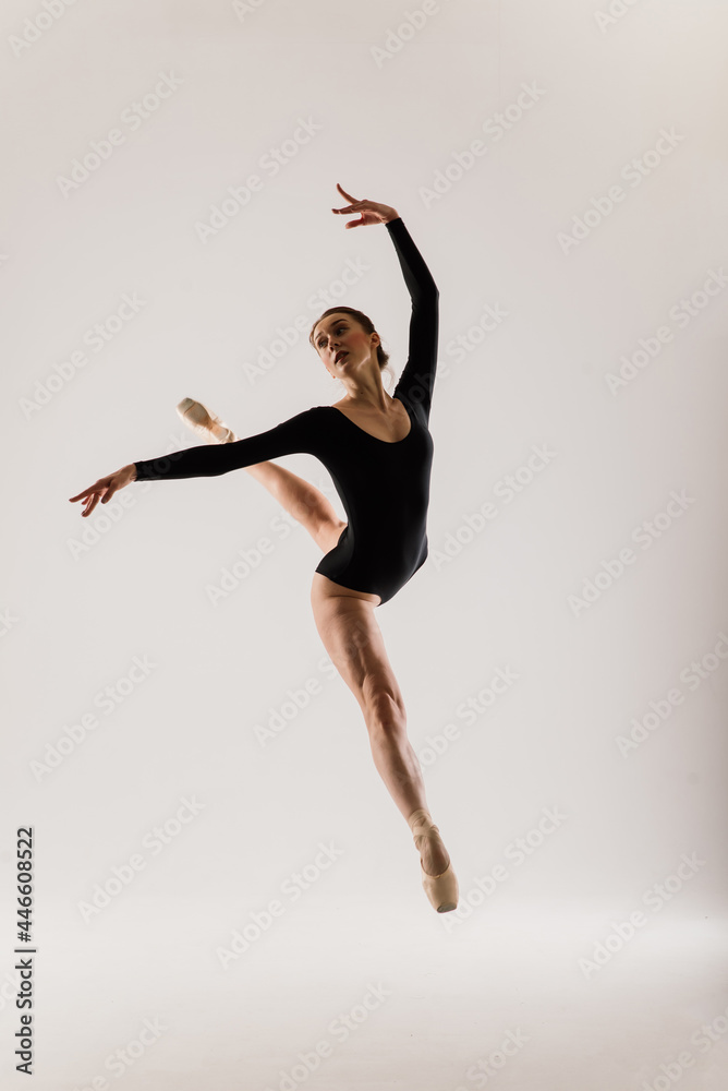 Portarit of Sensual professional caucasian callet dancer in body suit and pointes shoes on white.