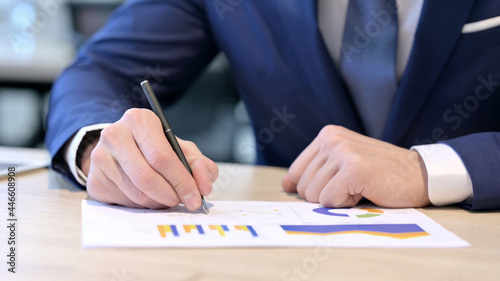 Close up of Hands of Businessman Studying Reports on Paper