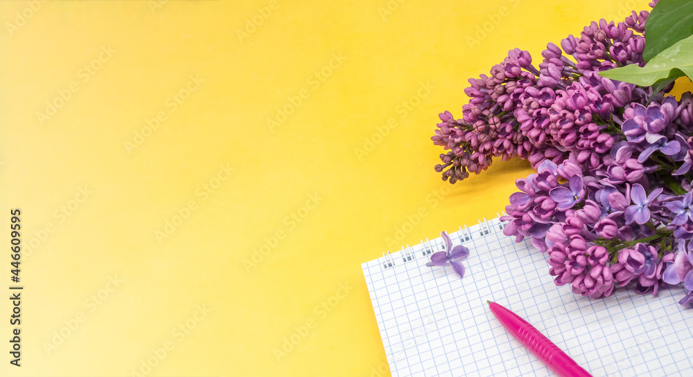 Spiral notebook and pen. Notepad with pen and flowers. Notebook lilacs on yellow background. Spiral notebook and pen. Notepad with pen and flowers. Notebook lilacs on yellow background.