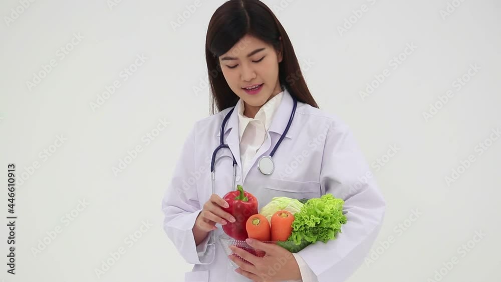 Asian female doctor or nutritionist have a beautiful smile wearing a white uniform Hold a bowl of fresh, organic vegetables. The concept of eating healthy food, taking care of your health. Asian female doctor or nutritionist have a beautiful smile wearing a white uniform Hold a bowl of fresh, organic vegetables. The concept of eating healthy food, taking care of your health.