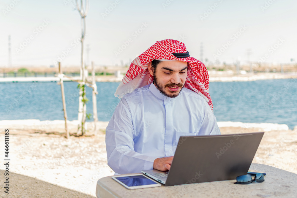 Smile Arab man working on the tablet and a laptop at maritime area in Middle East.