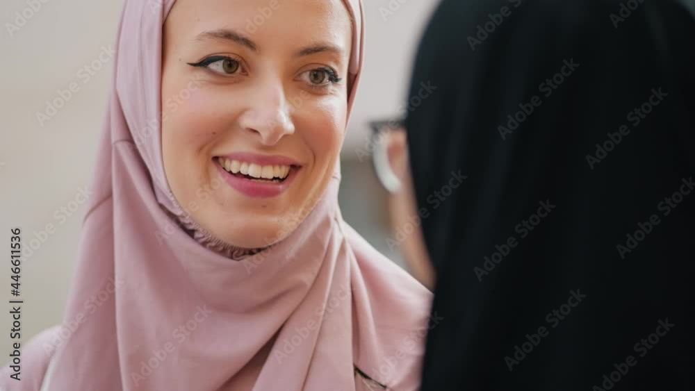 Close-up view of a smiling arabian women wearing national hijab is talking to her friend standing outside on the street Close-up view of a smiling arabian women wearing national hijab is talking to her friend standing outside on the street