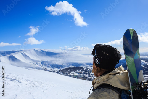 snowboarder with headphones on the top of snow mountain looking for road