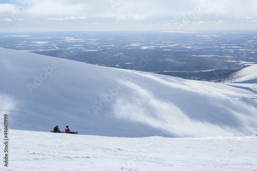 two snowboarders on the mountain and arctic winter lanscape behind them in polar russian ski resort