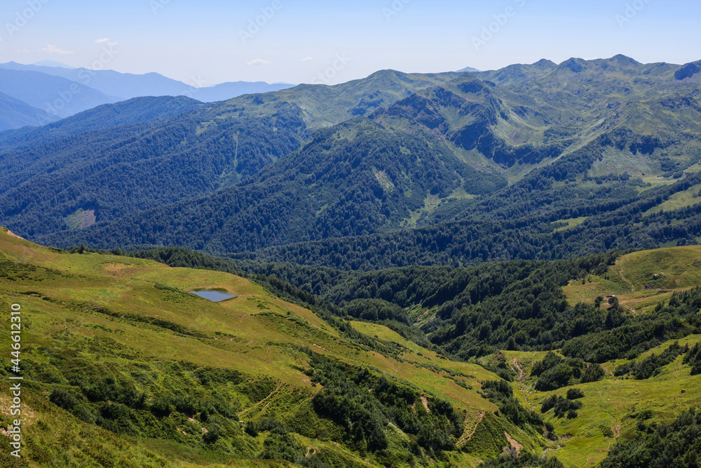 view of mountain lake and alpine meadows in covered with forest caucasus mountains