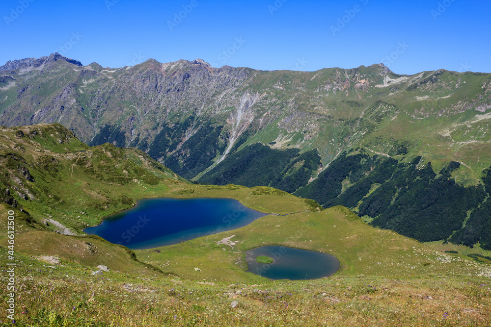 blue sky and blue water og the two mountain lakes surroubded with alpine meadows and high rocky mountains