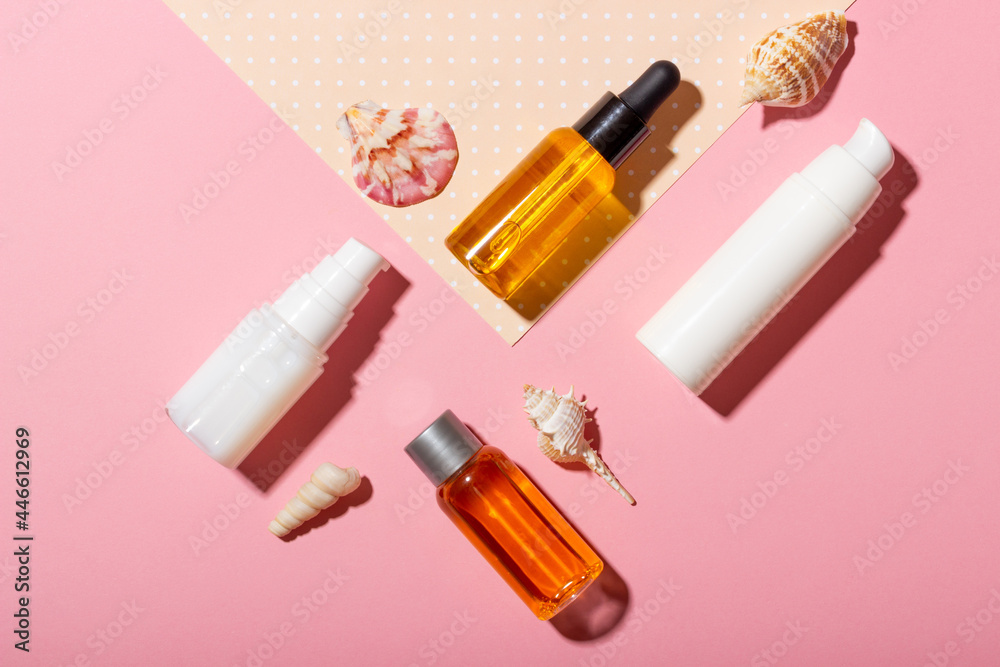 Tanning oil. Cosmetic products next to seashells in sunbeams on a pink background. Sun protective cosmetics. Tanning oil. Cosmetic products next to seashells in sunbeams on a pink background. Sun protective cosmetics.