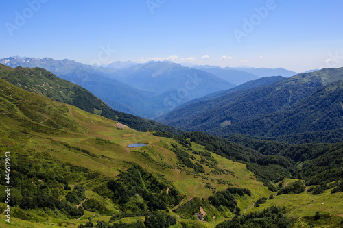 small mountain lake on the alpine meadows and valley covered with forest in caucasus