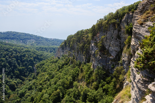 small village in caucasus mountains and high rocks covered with greenforest and pine trees