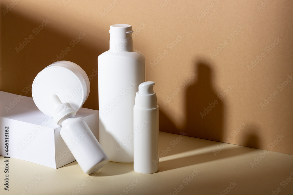 A set of female professional cosmetics for face and body care. Cosmetic tube with skin care product on beige background with hard shadows.