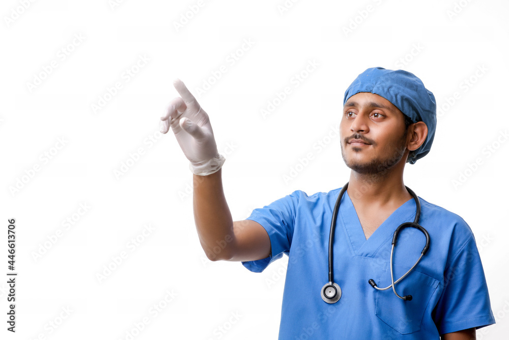 Young indian male doctor pointing with finger over white backgro Young indian male doctor pointing with finger over white backgro