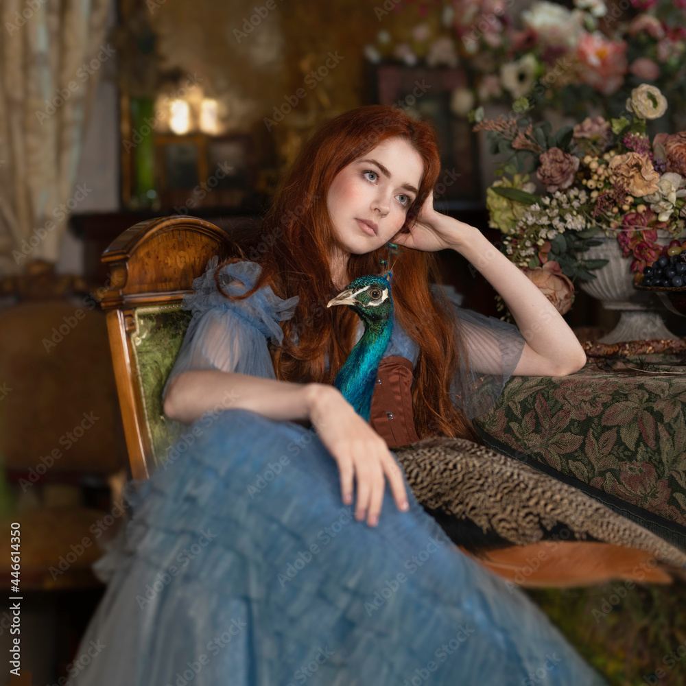 Red-haired woman in a chair with a blue peacock on her knees