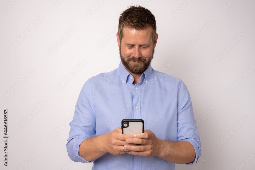 Smiling young good looking caucasian man using smartphone isolated over white background Smiling young good looking caucasian man using smartphone isolated over white background