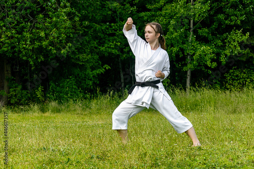 teenage girl training karate kata outdoors, performs age-uke (rising or upward block)