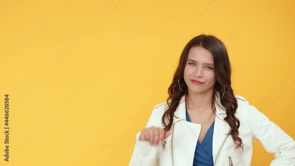 Choice disapproval. Dislike gesture. Bad idea. Dissatisfied joyful smiling brunette girl rejecting offer with thumb down hand nope sign isolated on orange copy space background. Choice disapproval. Dislike gesture. Bad idea. Dissatisfied joyful smiling brunette girl rejecting offer with thumb down hand nope sign isolated on orange copy space background.