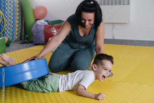 Rehabilitation of children with cerebral palsy. Physical activities for disabled kids in center. Mother, therapist doing exercise with boy on mat. Learning to move and communicate. Inclusion. 