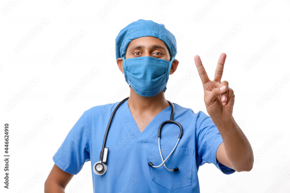 Young indian doctor showing victory sign over white background. Young indian doctor showing victory sign over white background.