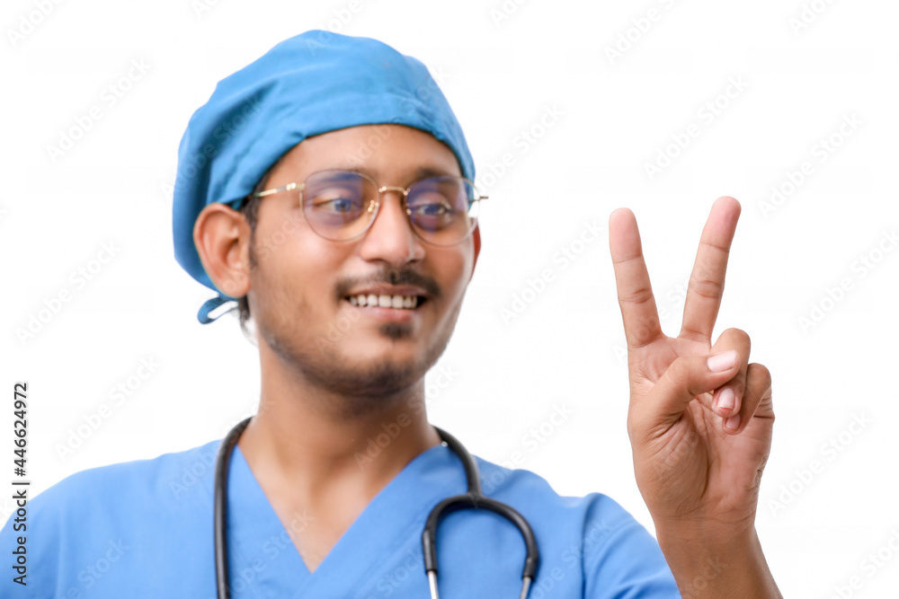 Young indian doctor showing victory sign over white background. Young indian doctor showing victory sign over white background.