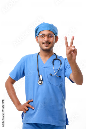 Young indian doctor showing victory sign over white background.