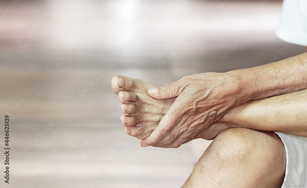 Fototapeta premium Close-up of a man's arm holding a painful foot caused by vaccination. Neurological concept, numb hands and feet
