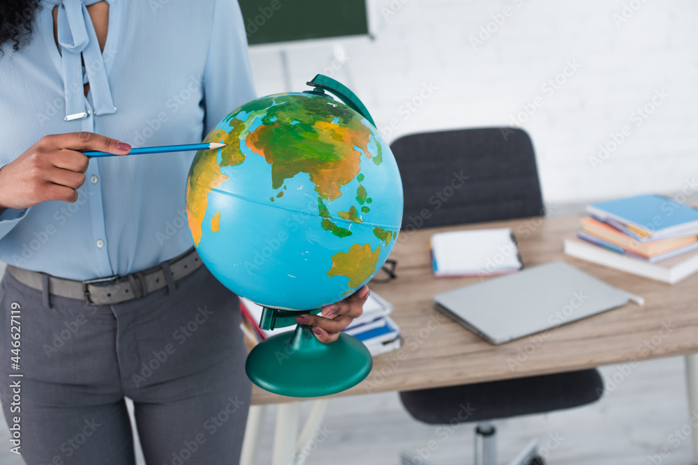 Cropped view of african american teacher pointing at globe with pencil Cropped view of african american teacher pointing at globe with pencil