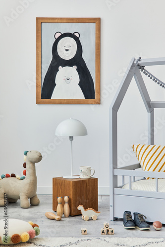 Stylish scandinavian child's room interior with mock up poster frame, creative bed, wooden cube, lamp, plush and wooden toys and hanging textile decorations. Grey walls, carpet on the floor. Template.